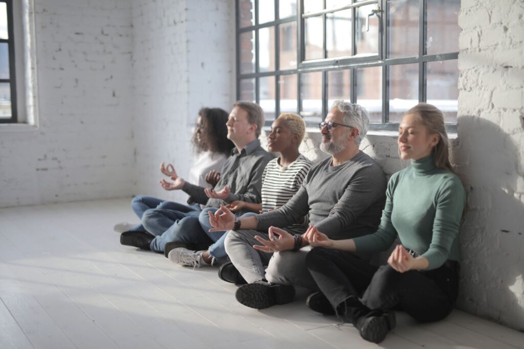 Grupo de pessoas a praticar meditação sentados no chão